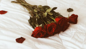 A bouquet of red roses lying on white sheets